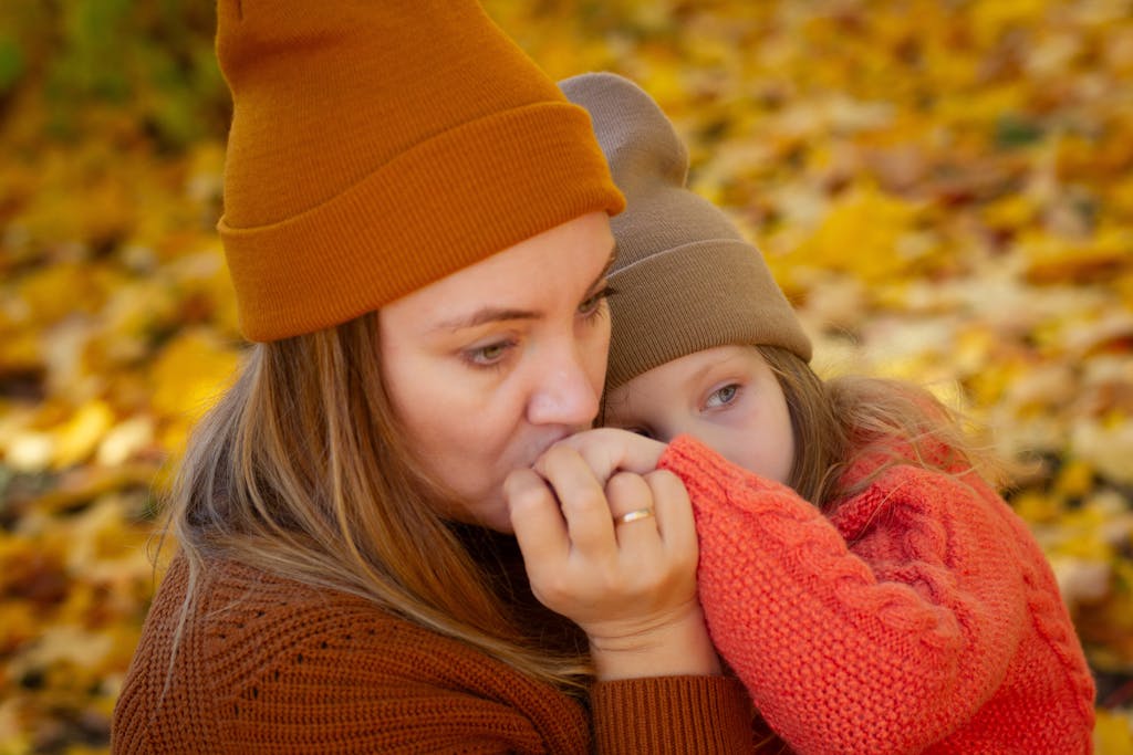 a mother and daughter share a tender moment surrounded by vibrant fall leaves. 33610157